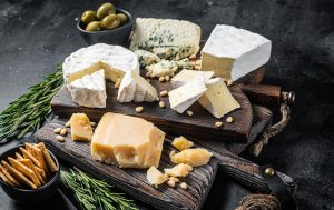 Appetitlich angerichtete Auswahl verschiedener Käsesorten auf einer Holzplatte, darunter gereifter Hartkäse und Weichkäse. Das Bild steht exemplarisch für histaminreiche Lebensmittel wie Käse, die bei Menschen mit Histaminintoleranz Unverträglichkeitsreaktionen auslösen können – etwa Hautrötungen, Juckreiz oder Kopfschmerzen – obwohl keine allergische Reaktion vorliegt.